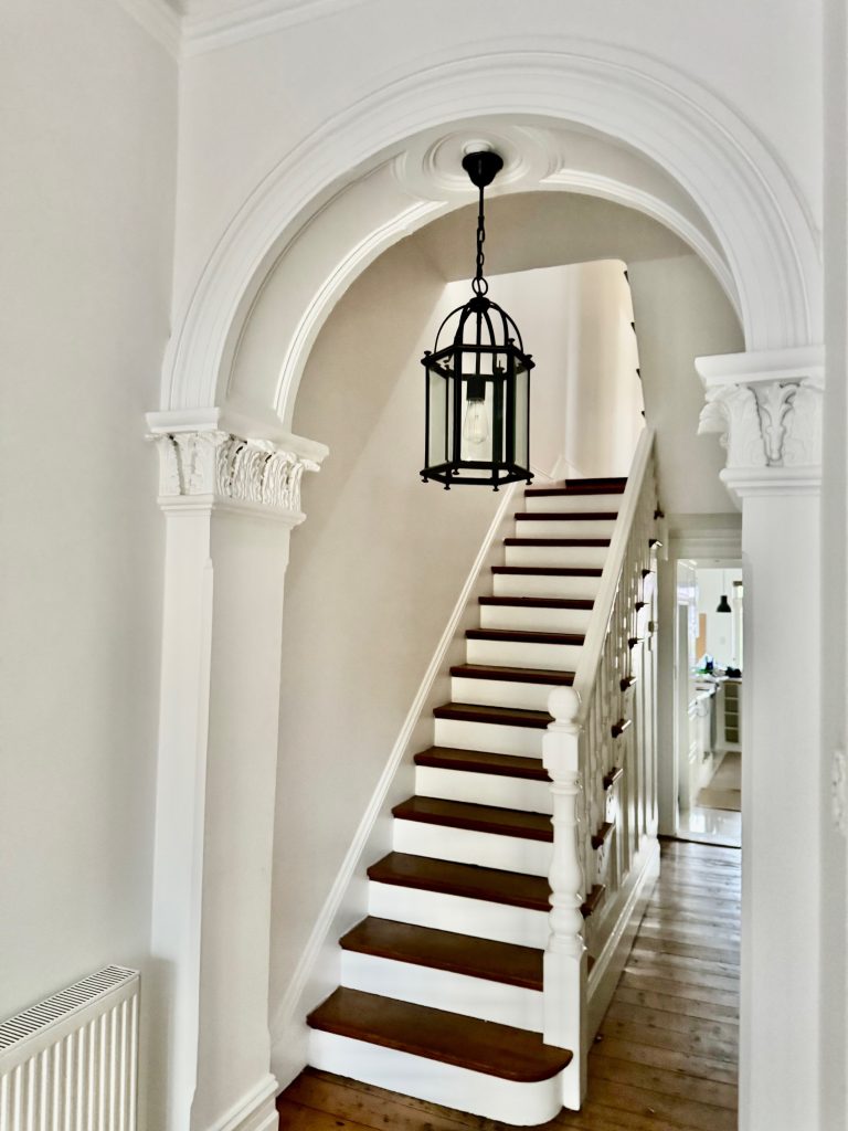 Heritage hallway repaint in Petersham with ornate arch and staircase detail