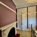 Bedroom with heritage fireplace, decorative cornices and painted wall panels in Enmore home