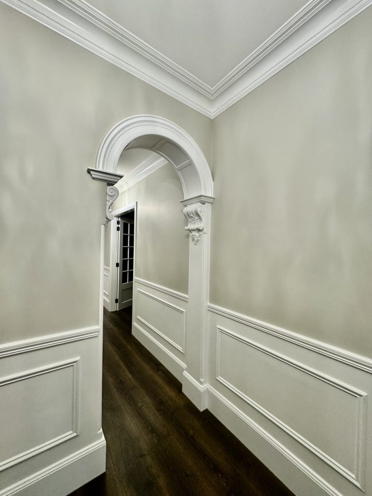 Interior hallway with decorative archway, wall panelling and detailed trim painting in Ashbury home
