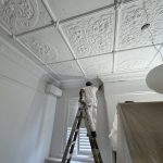 Professional painter restoring ornate pressed metal ceiling in Summer Hill heritage home