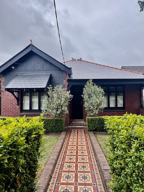 Federation house with dark heritage colours, brickwork and tessellated tile path