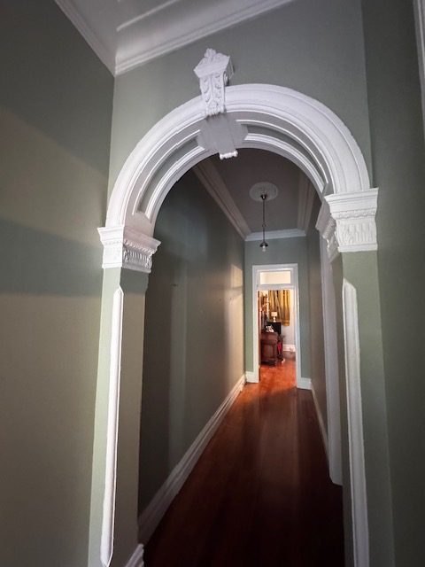 Heritage hallway with muted wall colour, white decorative arch and timber floors