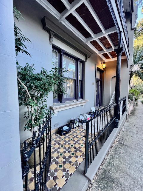 Heritage house exterior with light walls, dark window trims and traditional verandah