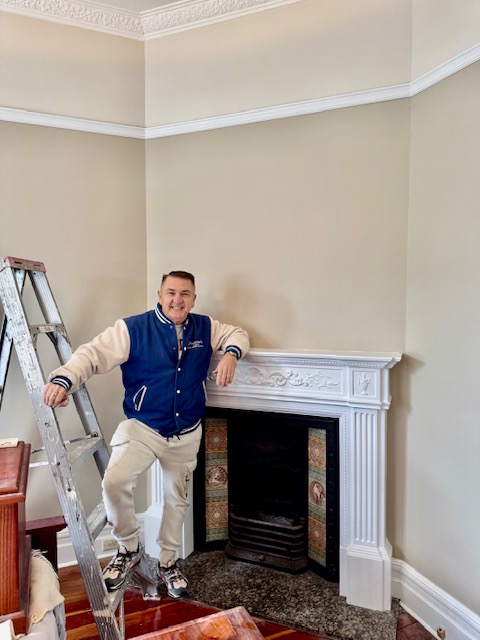 Heritage interior with neutral wall colour, white decorative fireplace and ornate ceiling